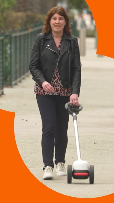Emma Tracey uses a Glide - a device with two wheels and a long handle - on a walkway