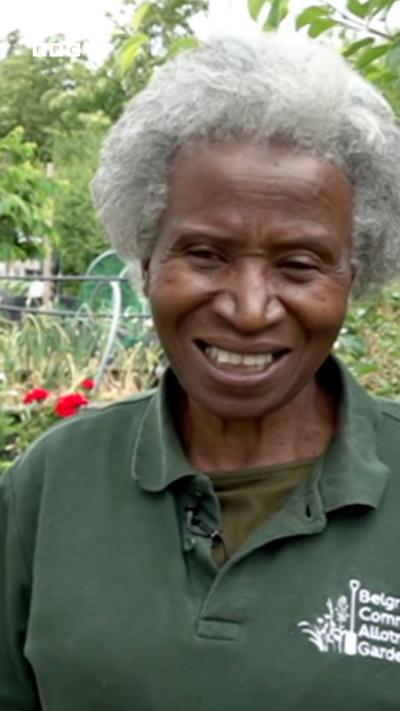 A black woman with grey hair wearing a green polo shirt