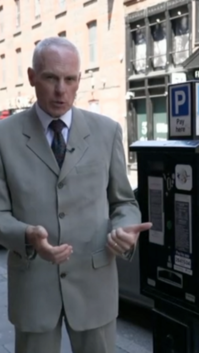 A man in a suit infront of a pay and display machine
