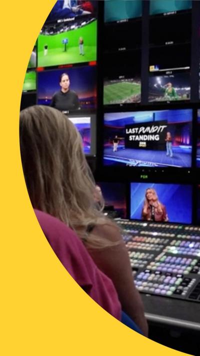 A person watches multiple monitors in a TV studio gallery 