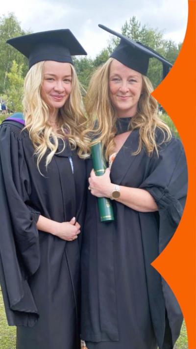 Mother and daughter wearing a cap and gown at their graduation.