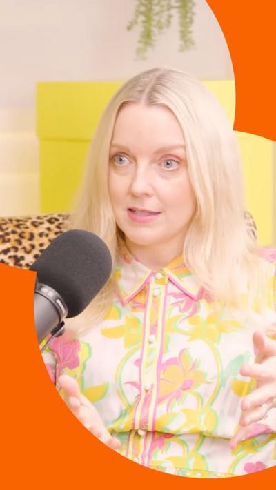 A woman with shoulder-length blonde hair talks into a microphone