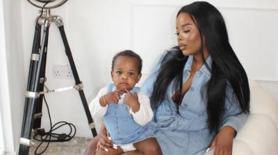 Tawana Musvaburi poses with her child. They both wear light blue denim.