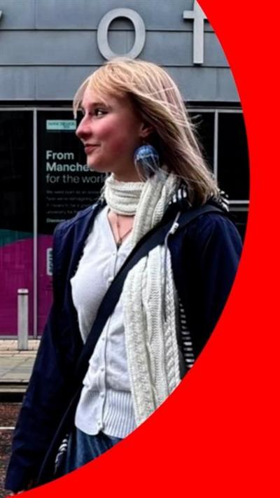 Young woman with blonde hair, looking to her right with a smile in a street.