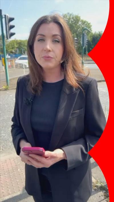 BBC reporter in black jacket by the road.