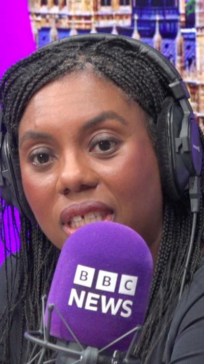 A woman sits in a purple radio studio