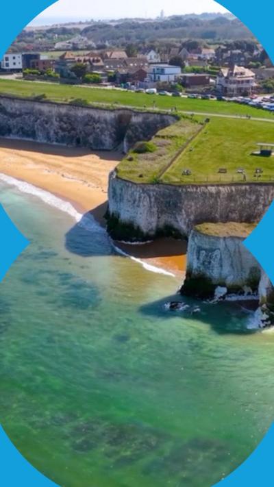 Arial shot of grass topped white cliffs towering above the ocean 