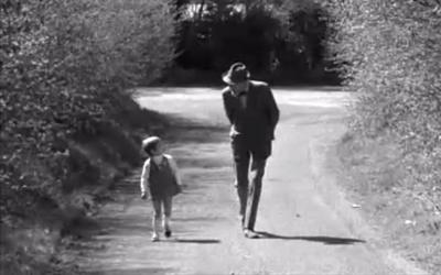 Fyfe Robertson and Louise walk side by side, on a sunny road