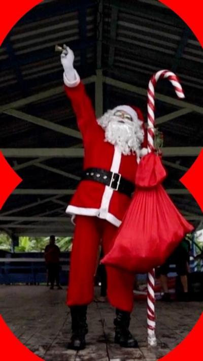 Someone dressed as Santa holds a hand up and holds a candy cane