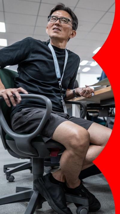 A man wearing shorts and sitting in an office chair