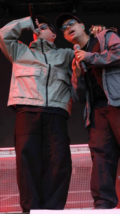 Two member of Kneecap on stage singing into microphones 