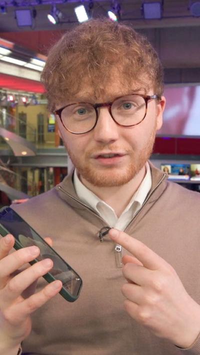 Thomas C holding up a phone and pointing at it