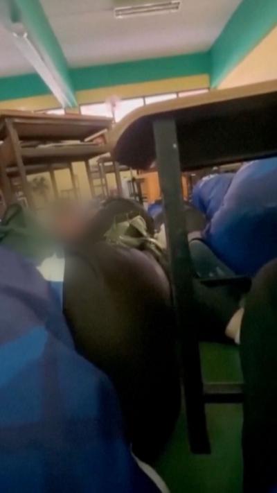 Student taking cover under desk films classmates also taking cover in classroom