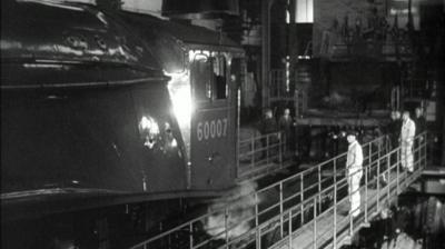 Workers stand on a walkway in front of a train.