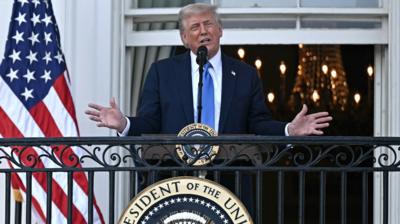Donald Trump stands on a balcony outside the White House