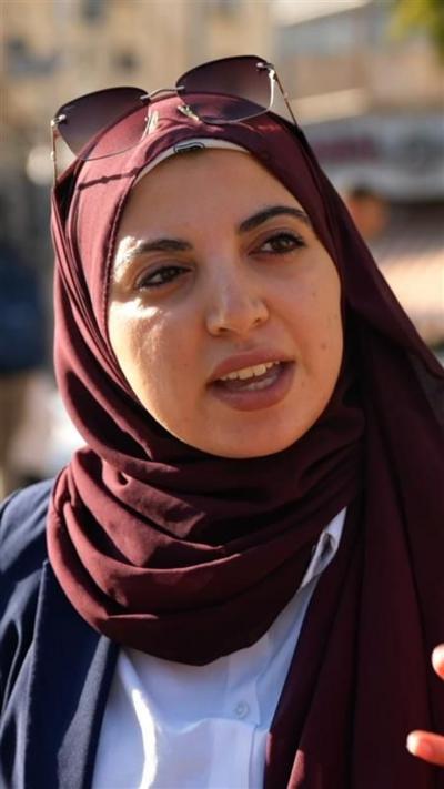 A woman wearing a burgundy headscarf, with sunglasses on top of her head