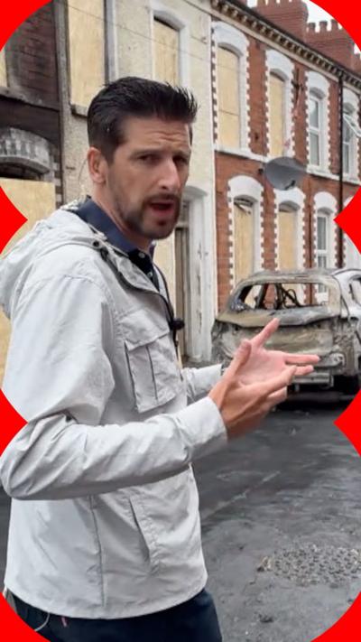Correspondent Dan Johnson reporting from Belfast street where a burnt car is seen