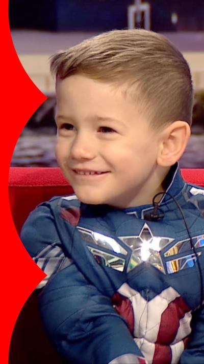 A little boy smiles. He's wearing a Captain America costume