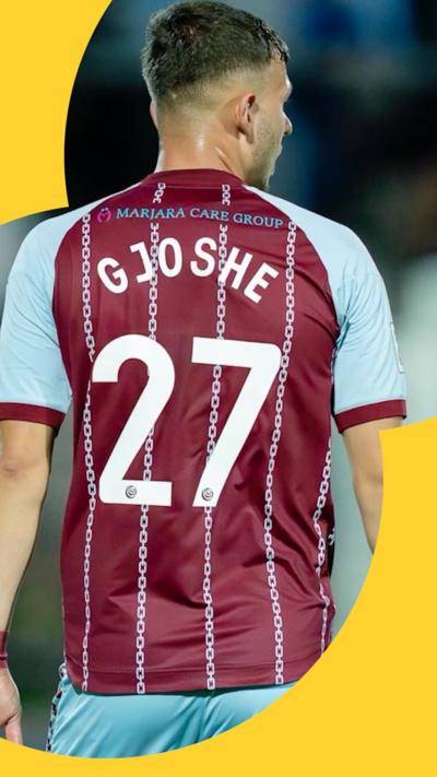A man in a burgundy and blue football kit stands with his back to the camera