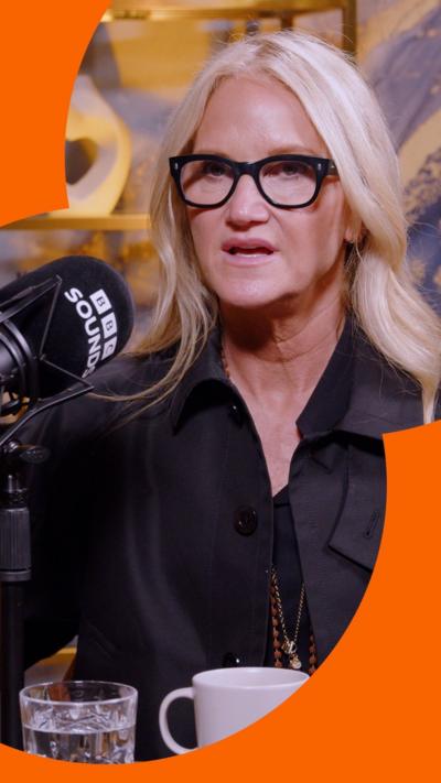Author Mel Robbins speaks into a BBC microphone wearing a black jacket and glasses