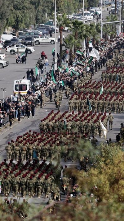 The military parades in Damascus as crowds line up to watch, many holding Syrian flags
