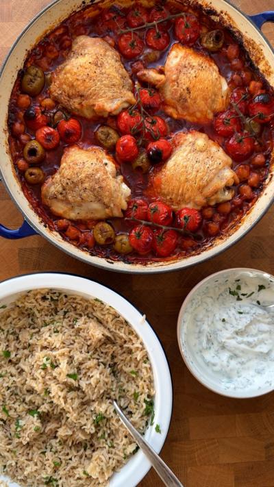 A pan of harissa chicken with chickpeas and tomatoes, next to a bowl of brown rice and another of mint yoghurt dressing.