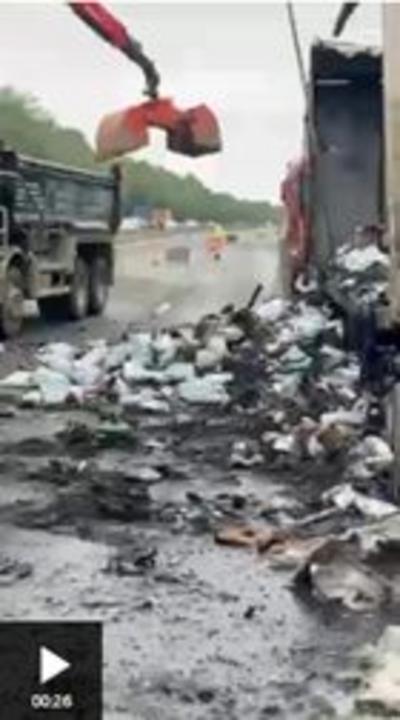 A burnt out lorry and a pile of unidentifable burnt objects strewn across a road.