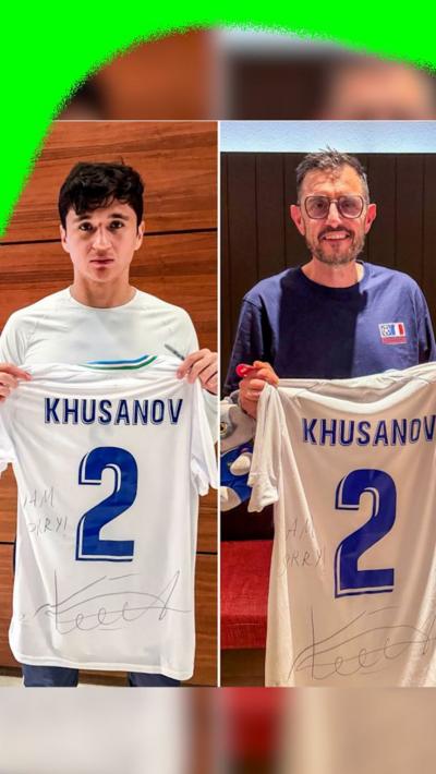 Abdukodir Khusanov gifts the cameraman a signed shirt after tackling him at Uzbekistan v Columbia at the 2026 World Cup.