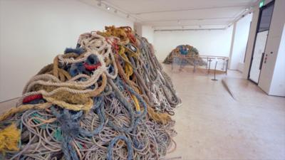 Two large piles of multicoloured rope in an art gallery