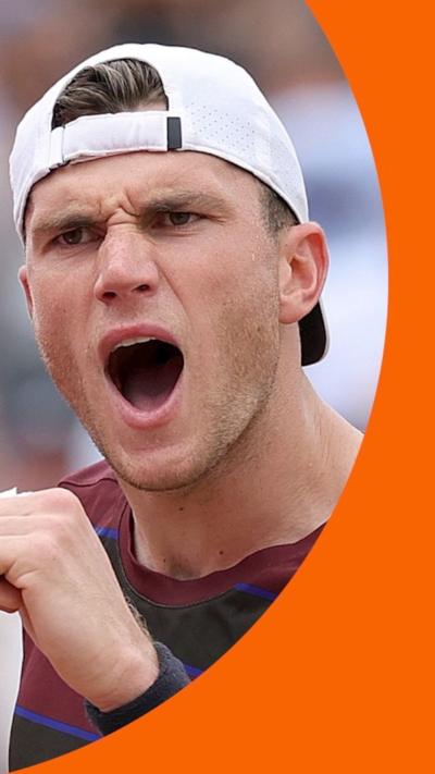 Jack Draper with a focused look. He's wearing a backwards white cap and has his arm raised in a fist pump