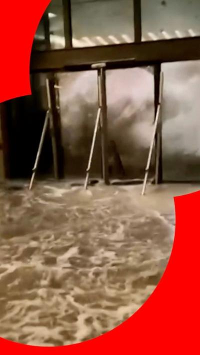 A wall of water bursting through a hotel's glass doors