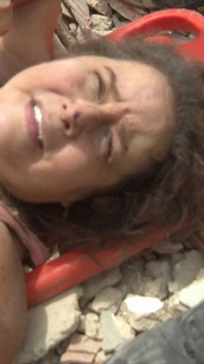 A woman being pulled from rubble alive