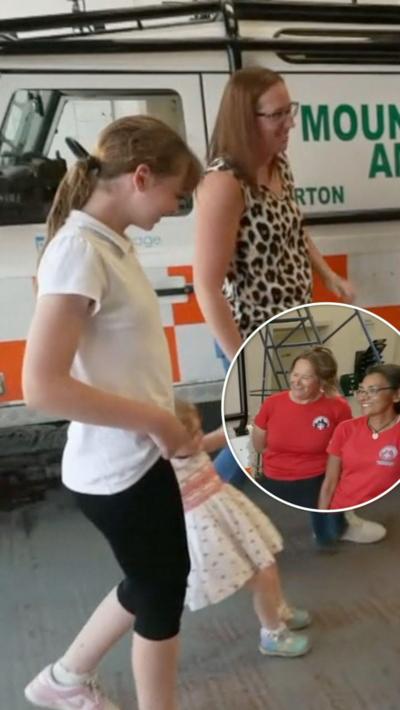 Shannon and her mum and younger sister walking next to a mountain rescue vehicle. In a white circle are two women in red tops. 