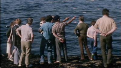 A group of people stand on a sea shore