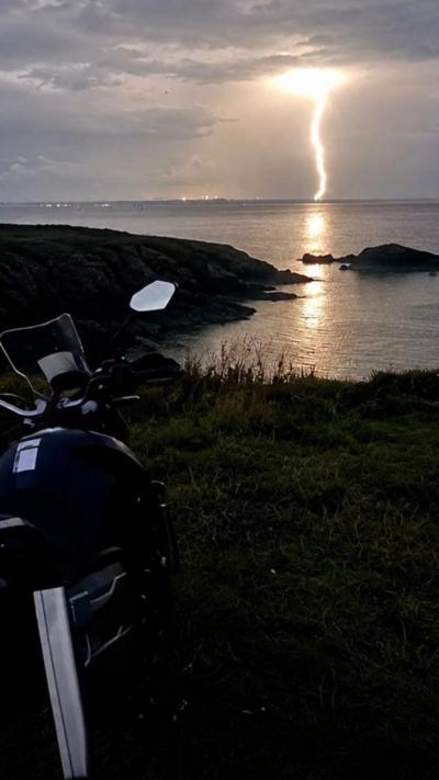 A lightning strike over a bat with a motorcycle in the foreground