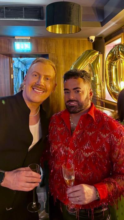 A man in a black shirt, and next to him a man in a red shirt