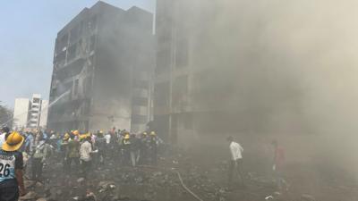 Rescue team members work as smoke rise at the crash site where an Air India plane crashed in Ahmedabad, India