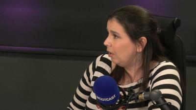 Falkirk councillor Laura Murtagh sitting in the Scotcast studio, she has shoulder length dark hair and a black and white striped top.