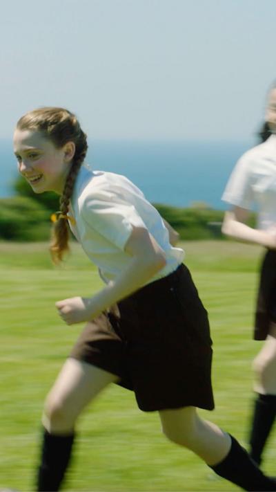 A young girl plays football on a field.