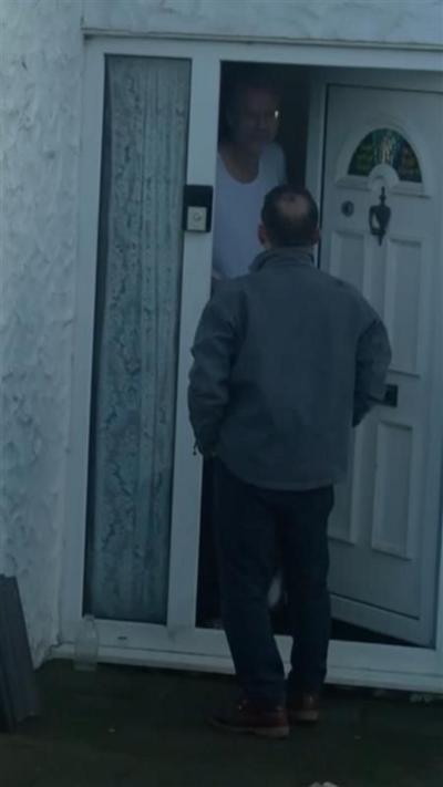 Wyre Davies facing a door which is held ajar by Nathan Gill