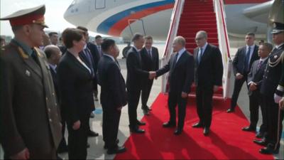 Putin shaking hands with a member of the Chinese delegation