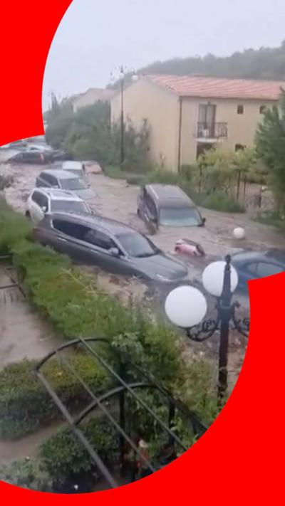 Cars being swept down street in floodwaters
