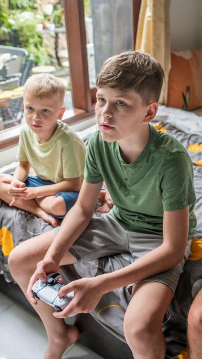 Two boys play video games in their bedroom