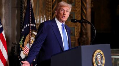 Donald Trump stands at a podium.