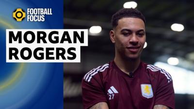 Morgan Rogers smiles in a maroon and light blue Aston Villa training top