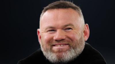 Wayne Rooney smiling against a black background