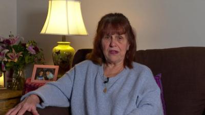 Margaret Mizen wearing a light blue jumper sitting on a sofa speaking to the camera.