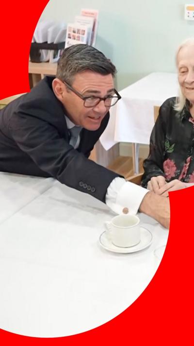Andy Burnham reaching across a table to shake someone's hand