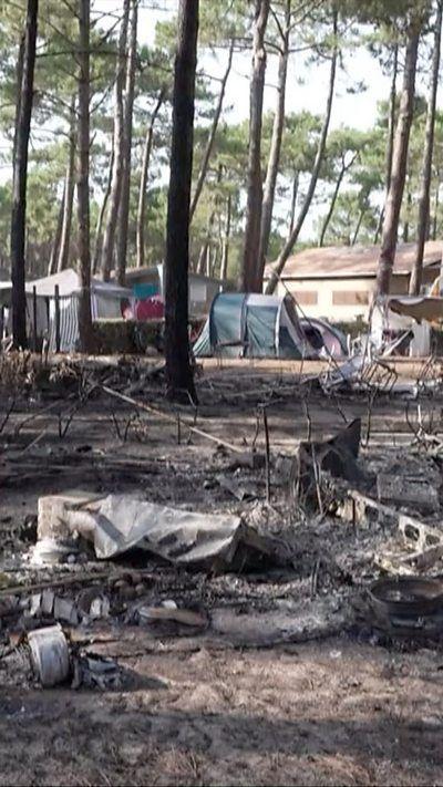 Vertical image which shows an empty campsite with burnt out items on the ground