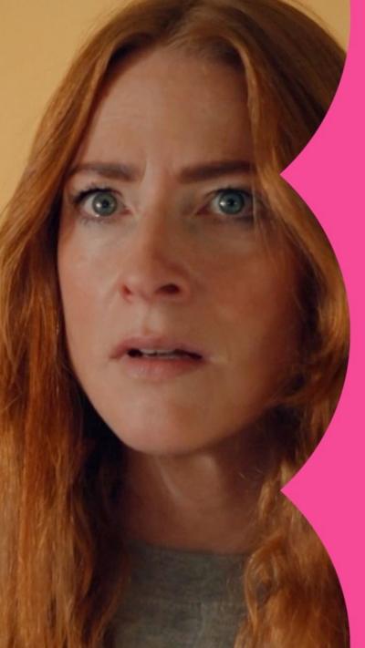 A woman with long ginger hair - Kitty - looks shocked.